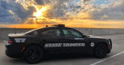 Passenger side of a Nebraska State Patrol Cruiser with a sun set in the background.